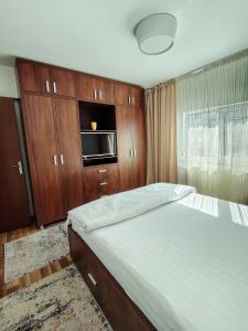 a bedroom with a bed and a tv and wooden cabinets at Adrian Home Mega in Ploieşti