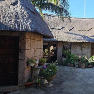 a building with a thatch roof with potted plants at Afrika Lodge in Kempton Park
