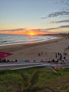 a beach with a sunset and people on the beach at CARAVELL ARMAÇÃO de PÊRA in Armação de Pêra