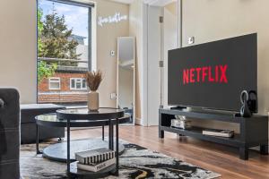 a living room with a television on a table at Premium Apartment Steps from Wembley Park in London
