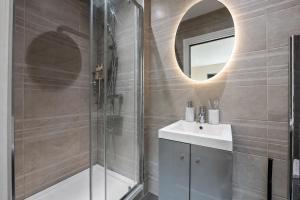 a bathroom with a shower and a sink and a mirror at Premium Apartment Steps from Wembley Park in London +26 photos