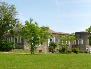 una vecchia casa in pietra con un albero nel cortile di Ancien Haras de la Tour a Lamothe-Landerron