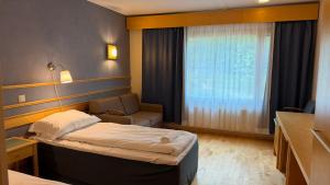 a bedroom with a bed and a couch and a window at Tiera Resort in Taivalkoski