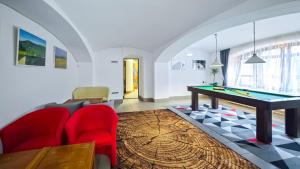 a living room with a pool table and red chairs at Penzion Vápenka in Horní Maršov