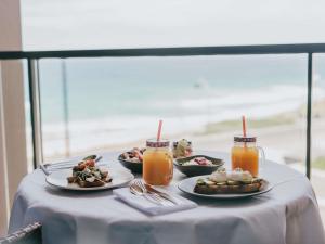 a table with plates of food and glasses of juice at Novotel Newcastle Beach in Newcastle