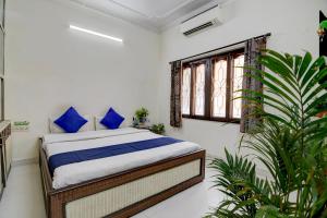 a bedroom with a bed with blue pillows and a window at Hotel Elguse in kolkata +23 photos