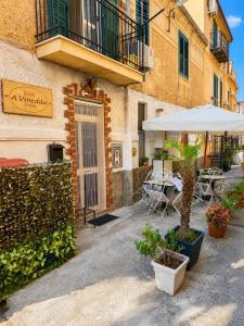 a patio with a table and an umbrella in front of a building at B&B A Vinedda in Scilla
