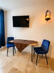 a dining room with a wooden table and two blue chairs at César Room - Appartement Antique 2-3 pers, parking privé,proche centre et gare in Obernai