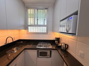 a kitchen with a stove and a microwave at Apto no centro - Praça Mini Golf - Sacada - Garagem - 300m do Mar - Térreo in Capão da Canoa +5 photos