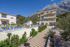 a hotel with a resort with chairs and mountains in the background at Dorijini Dvori in Baška Voda