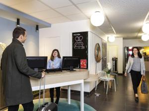 a man with a suitcase in a lobby with two women at Aparthotel Adagio Access Paris Reuilly in Paris