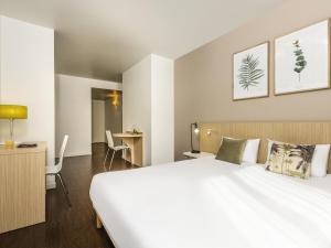a hotel room with a large white bed and a desk at Aparthotel Adagio Access Paris Reuilly in Paris