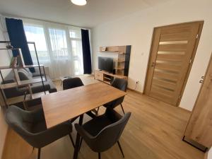 a living room with a wooden table and chairs at Nagyerdő Naplemente Apartman Debrecen in Debrecen