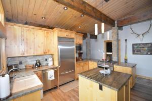 a kitchen with wooden cabinets and a stainless steel refrigerator at Deer Lodge #2- Lake Front in Bass Lake
