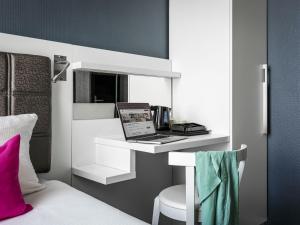 a room with a bed and a laptop on a desk at ibis Styles Amsterdam Amstel in Amsterdam