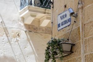 a street sign on the side of a building with a plant at Il rifugio barocco in Lecce +10 photos