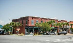 an old red brick building on a street with a street intersection at The Montgomery by Visit Apalach in Apalachicola