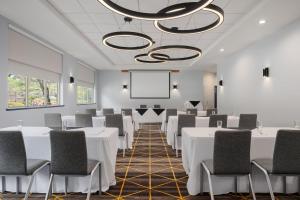 a conference room with white tables and chairs and a projection screen at Holiday Inn Victoria - Elk Lake by IHG in Victoria +110 photos