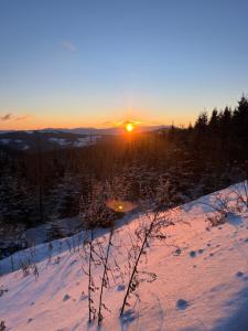a snow covered hill with the sun setting in the distance at Das Zehnerkar Chalet - Klippitztörl in Kliening