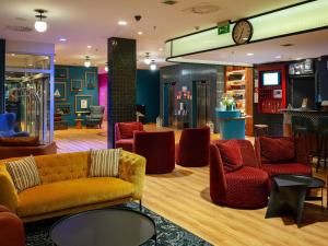 a lobby with couches and chairs and a clock at ibis Styles Wałbrzych in Wałbrzych