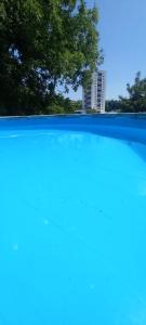a blue pool with a tree in the background at Stan na dan Apartman Durakovic in Cazin +11 photos