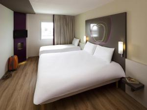 a hotel room with two beds and a mirror at Hotel Ibis Styles Lleida Torrefarrera in Lleida