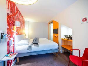 a bedroom with a white bed and a red chair at ibis Styles Paris La Défense Courbevoie in Courbevoie +56 photos