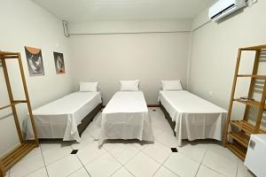 two beds in a room with white walls at Pousada Âncora - 14 Suítes completas com Ar, TV, Frigobar e Wi-Fi, para grupos ou viajantes individuais. in Gravataí