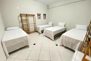 a room with two beds and a tiled floor at Pousada Âncora - 14 Suítes completas com Ar, TV, Frigobar e Wi-Fi, para grupos ou viajantes individuais. in Gravataí +64 photos