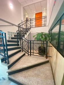 a staircase in a building with blue railings and plants at Pousada Âncora - 14 Suítes completas com Ar, TV, Frigobar e Wi-Fi, para grupos ou viajantes individuais. in Gravataí