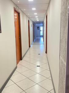 a hallway of an office building with a tile floor at Pousada Âncora - 14 Suítes completas com Ar, TV, Frigobar e Wi-Fi, para grupos ou viajantes individuais. in Gravataí