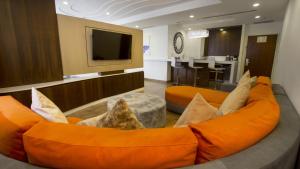 a living room with an orange couch and a tv at HS HOTSSON Hotel Queretaro in Querétaro