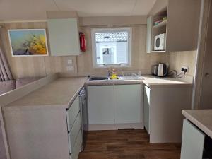 a small kitchen with white cabinets and a sink at 2 bedrooms caravan with a sea view in Poole