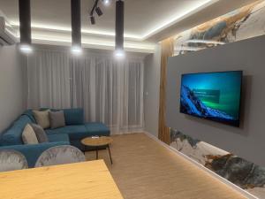 a living room with a blue couch and a tv on a wall at RICH 2 Apartment in Plovdiv +3 photos