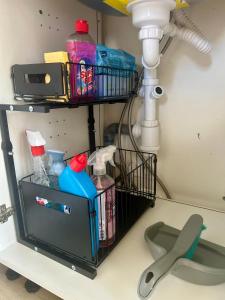 a shelf under a sink with cleaning supplies at Studio cosy 71 in Saint-Vallier +8 photos