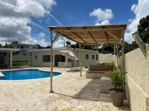 a wooden pergola next to a swimming pool at Casa Kaibana - 6 Pax, con piscina, cerca del mar in Las Galeras