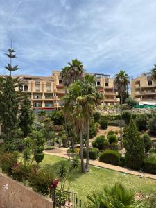 a park with palm trees and a building at A spacious apartment with an ocean view in Mijas Costa