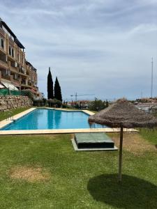 an umbrella sitting in the grass next to a swimming pool at A spacious apartment with an ocean view in Mijas Costa