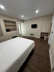 a bedroom with a large white bed and a tv at Casa da Praça- Boutique Rooms in Tavira