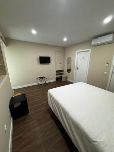 a bedroom with a white bed and a flat screen tv at Casa da Praça- Boutique Rooms in Tavira +20 photos