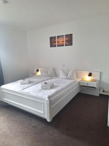 a large white bed in a room with two tables at Hotel am Zellwald in Großschirma