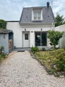 a white house with a door and a gravel driveway at La Blériotine in Sangatte