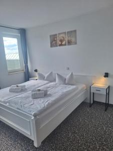 a bedroom with a large white bed with a window at Hotel am Zellwald in Großschirma