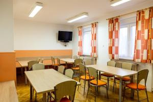 a classroom with tables and chairs and a tv at Hostel 1550 in Moravske-Toplice