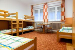 a dorm room with bunk beds and a table and chairs at Hostel 1550 in Moravske-Toplice