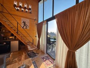 a living room with a staircase and a large window at West Coast Cottage Buknari in Buknari