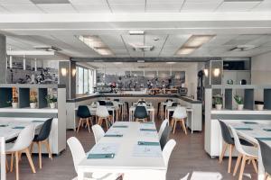 a restaurant with white tables and chairs and a kitchen at Hotel Imperiale in Cattolica
