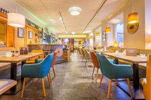 un restaurante con mesas de madera y sillas azules en Hotel Seehof, en Zell am See