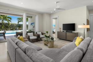 a living room with a large couch and a television at Second Wind Villa in Long Bay Hills