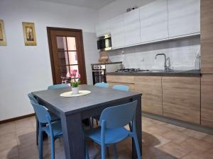 a kitchen with a table with blue chairs and a sink at Appartamento Felis in Molina di Ledro